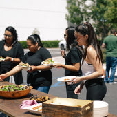 a photograph of happy NuFACE employees fixing salads at an outside salad bar