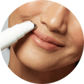 a photograph of a happy NuFACE woman using the FIX® device around her lips