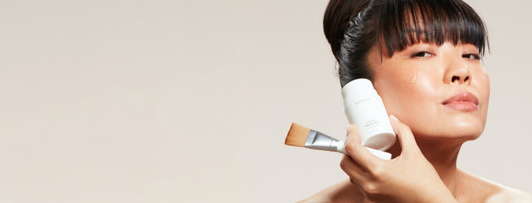 a photograph of a NuFACE customer holding the Aqua Gel and Brush by NuFACE by her cheek