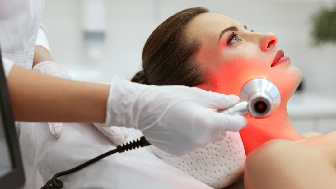 a photograph of a woman receiving red light treatment on her jawline from a specialist
